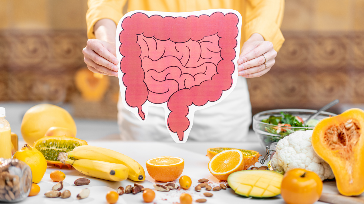 Person holding a gut illustration in front of a spread of fruit and vegetables