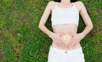 woman lying on a grass with hands placed on her stomach