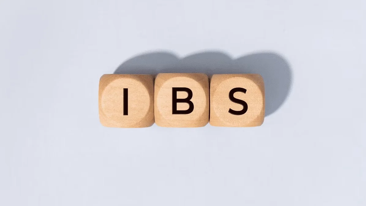 Wooden letter blocks spelling IBS on a light grey background